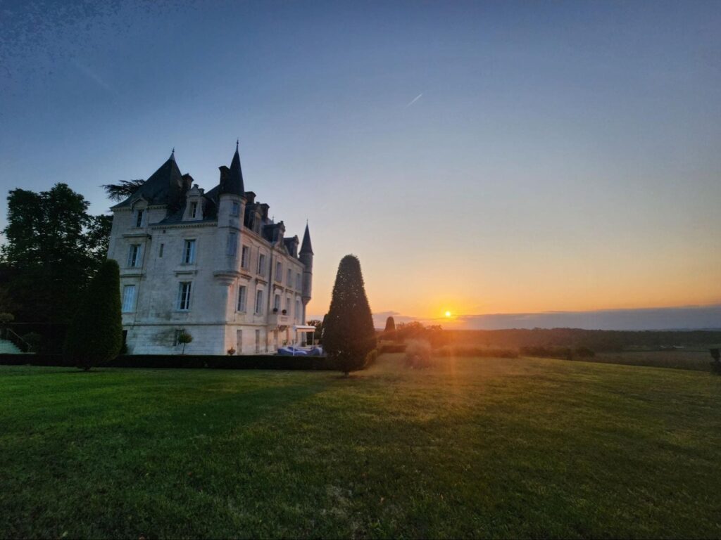 Photo at Château de Lasfonds. Sunset backdrop for a French chateau wedding.
