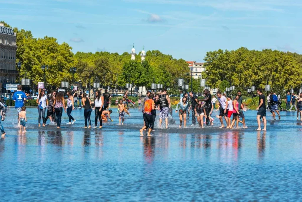 People having fun in a mirror fountain in front of Place de la Bourse in Bordeaux