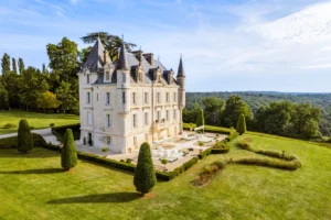 Aerial view of elegant countryside estate with pool and landscaped grounds, ideal example of a luxury chateau rental in France.