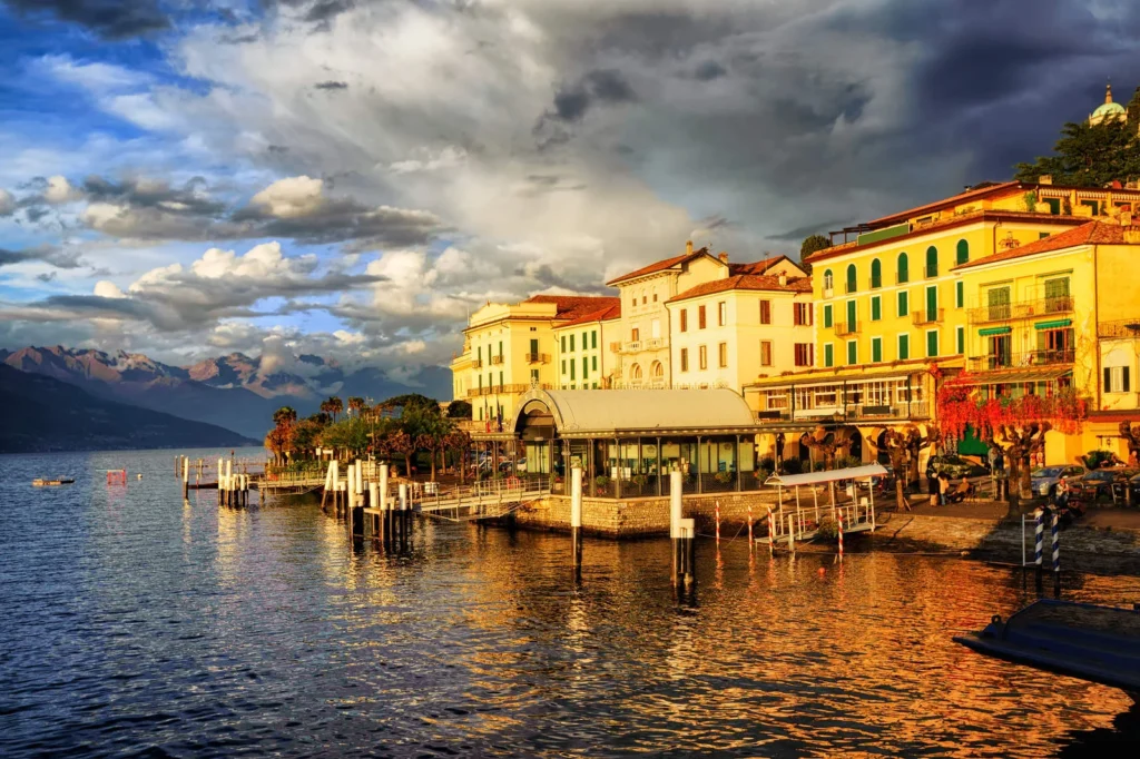 Waterfront view of Bellagio on Lake Como, featuring elegant pastel buildings, mountains, and reflections on the lake at golden hour.