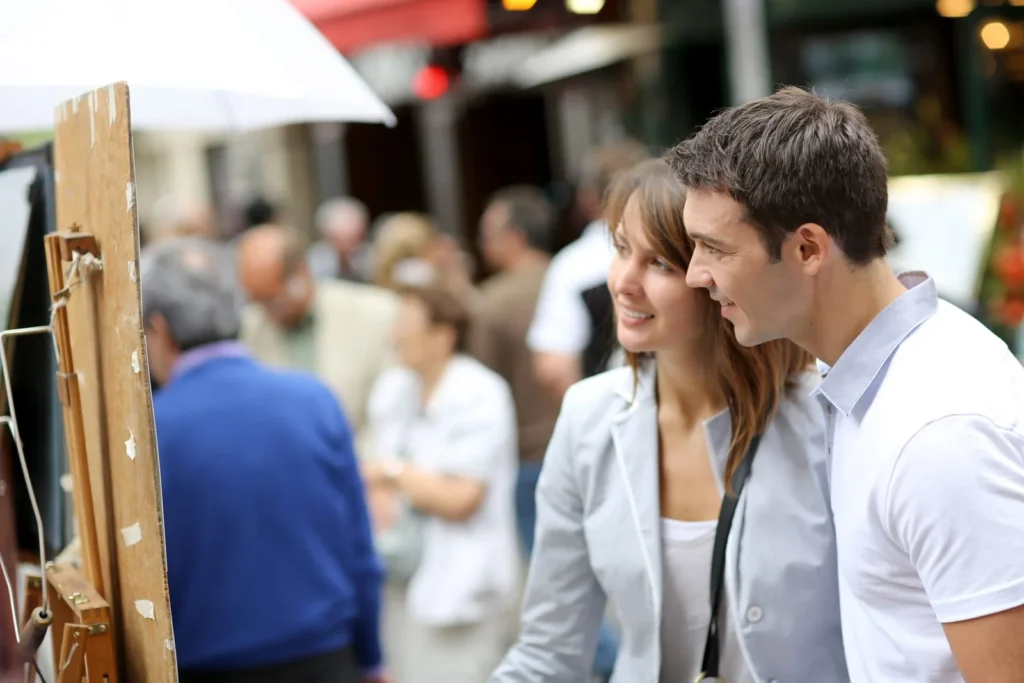 Couple exploring Paris street art market together, experiencing culture on their honeymoon in France