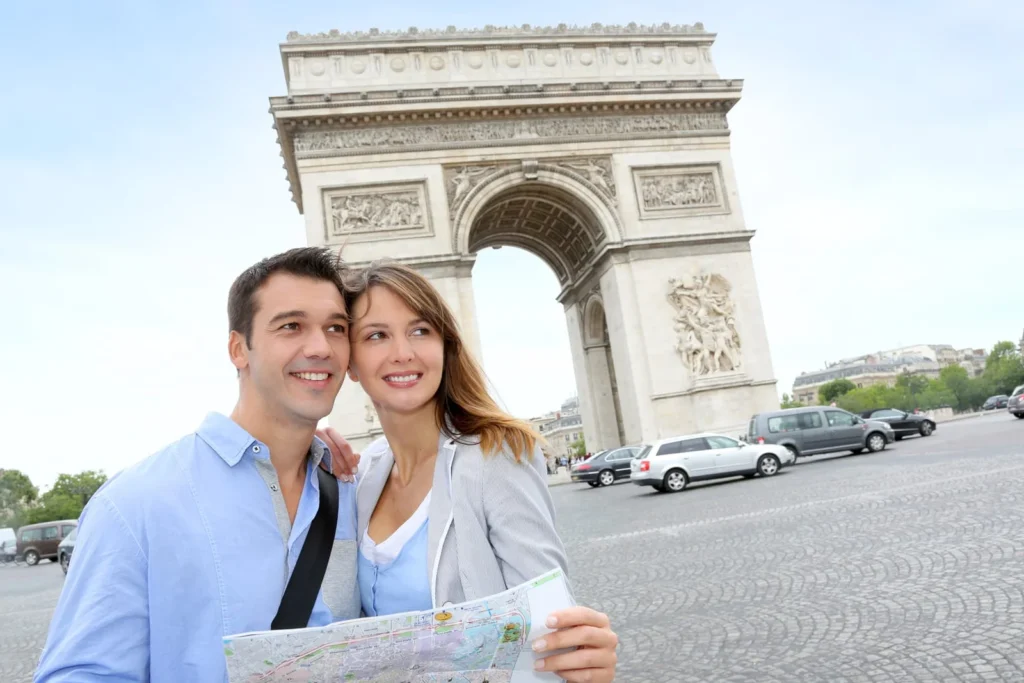 Newlywed couple reading a map near the Arc de Triomphe while sightseeing on their honeymoon in France