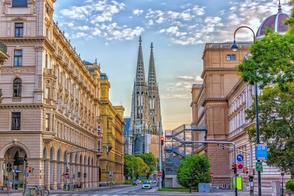 Votivkirche church rising above historic streets in central Vienna, framed by classical buildings and early evening light.