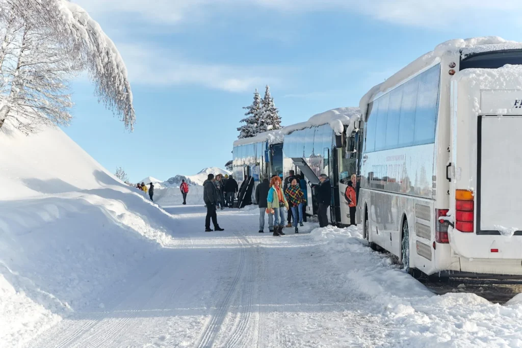 Travelers boarding bus in snowy mountain region of French Alps