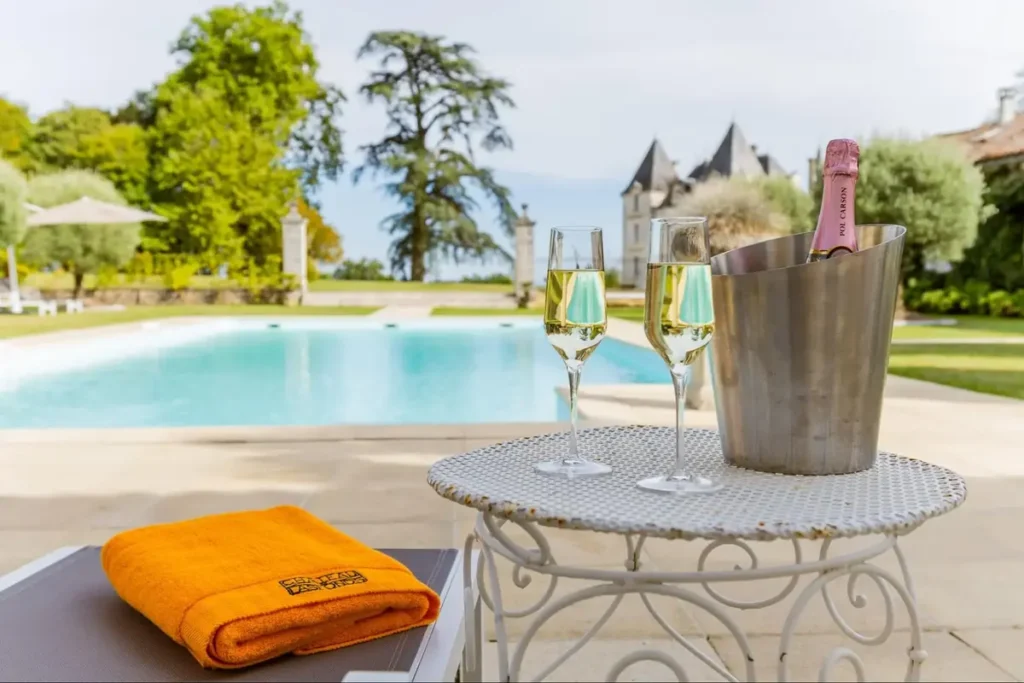 Poolside table with champagne glasses and bottle overlooking luxury estate garden
