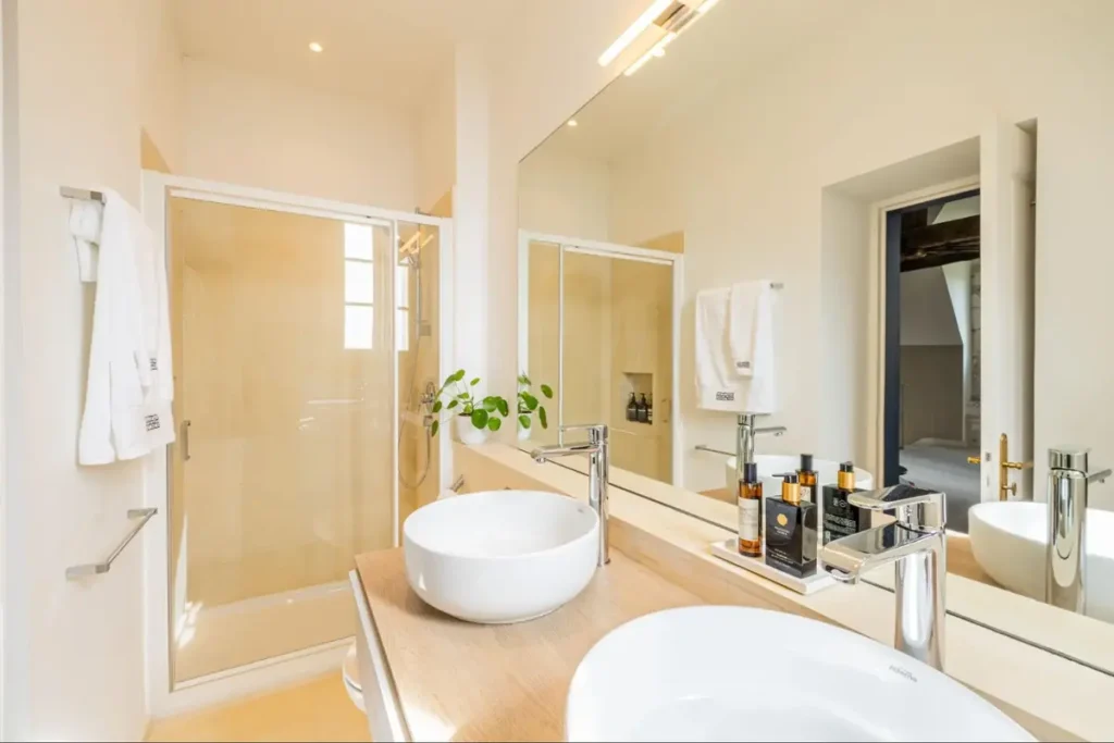 Modern bathroom with double sinks, mirror, and walk-in shower inside a château