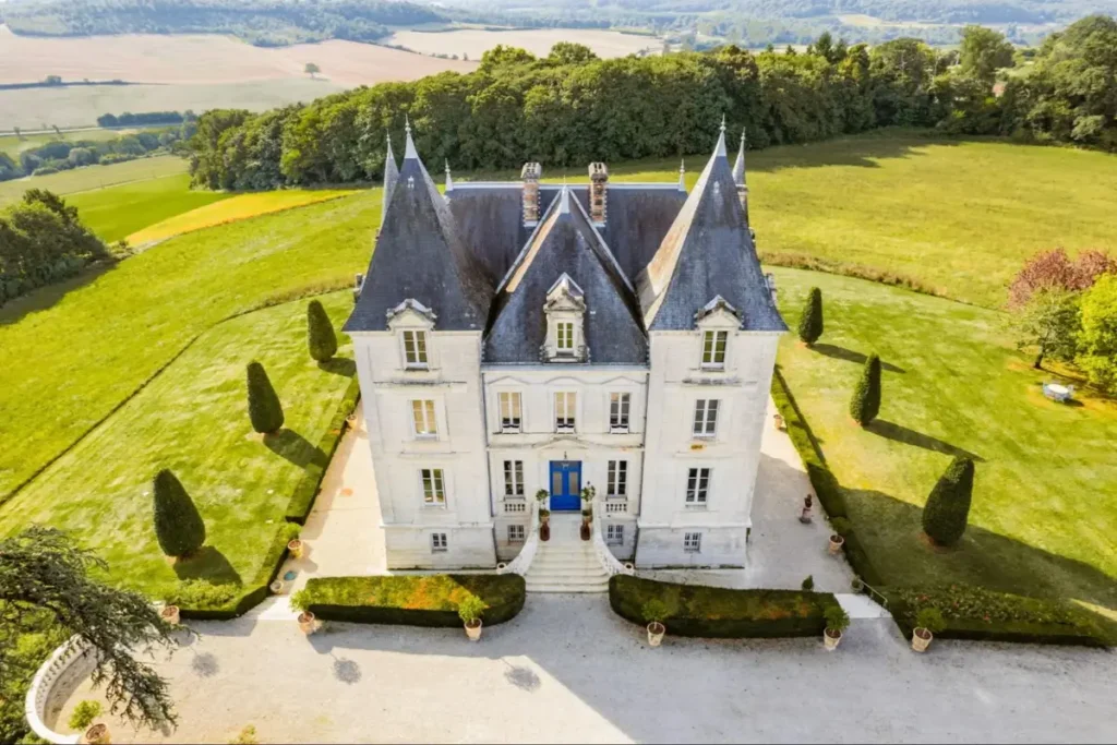Aerial view of Château de Lasfonds, a white French château surrounded by manicured lawns and rolling Dordogne countryside
