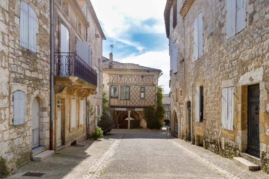 Narrow street in Monflanquin showing medieval architecture in France with stone facades, wooden shutters, and structured village layout