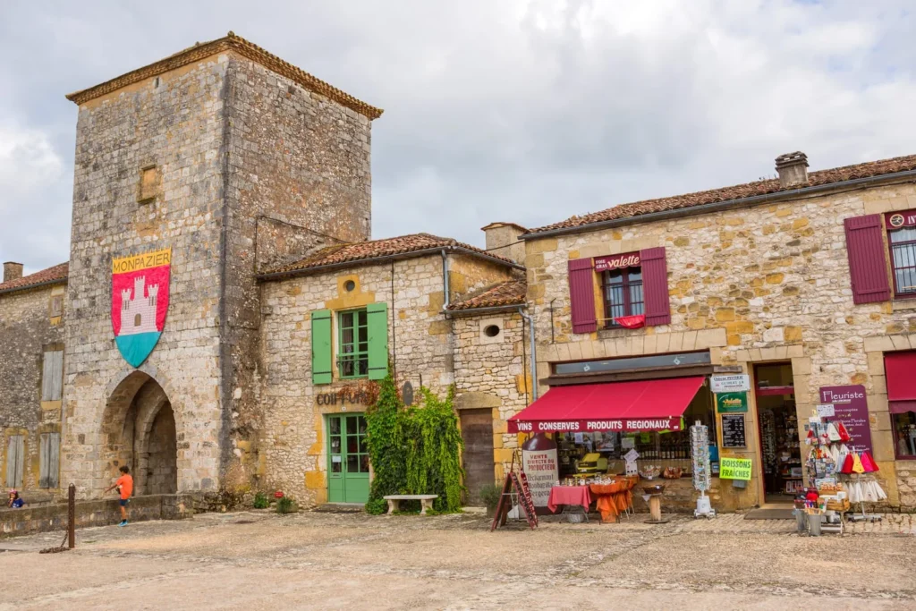 Entrance gate and shops in Monpazier, a preserved bastide town in France with central square design and historic stone buildings