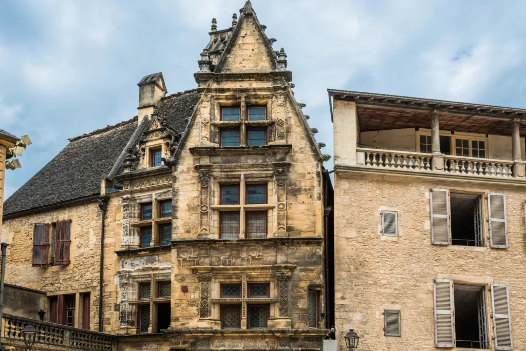 Detailed stone building facade in Sarlat, France highlighting medieval architecture, carved windows, and preserved urban heritage