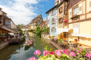 Colorful houses along canal in Colmar France with flowers and small boat