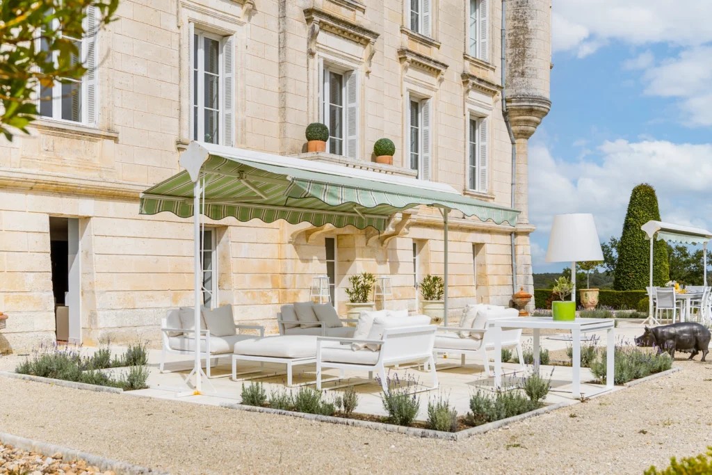 Outdoor terrace seating area beside château with garden views