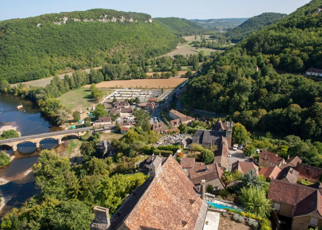 Aerial view of Dordogne valley village with river, bridge, and countryside landscape near popular canoe Dordogne routes