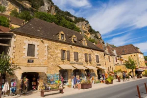 Stone houses and local shops in a Dordogne village with visitors walking along the street