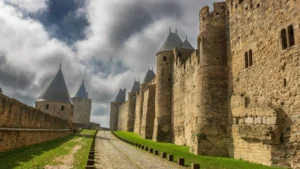 Medieval stone ramparts and towers of Carcassonne under a cloudy sky in France.