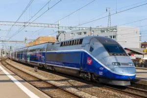 Blue SNCF TGV high speed train traveling through a French rail station