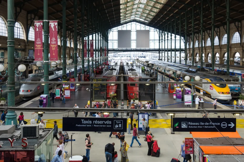 Busy French railway station with TGV and regional trains under a historic glass roof