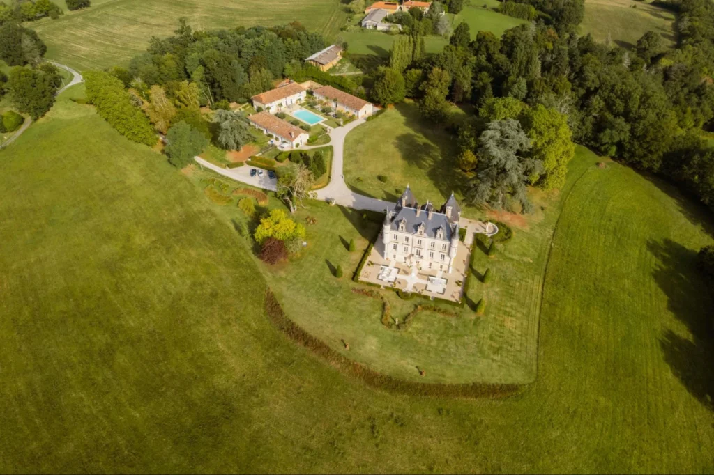 Aerial view of Château de Lasfonds estate with the main château, outbuildings, pool area, and surrounding countryside