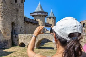 Tourist photographing Carcassonne Castle's medieval walls and towers in France.