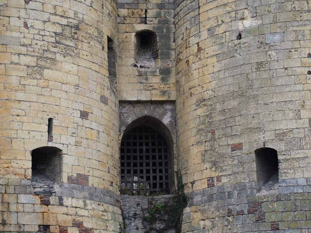 Stone castle gatehouse with a medieval portcullis and defensive towers.