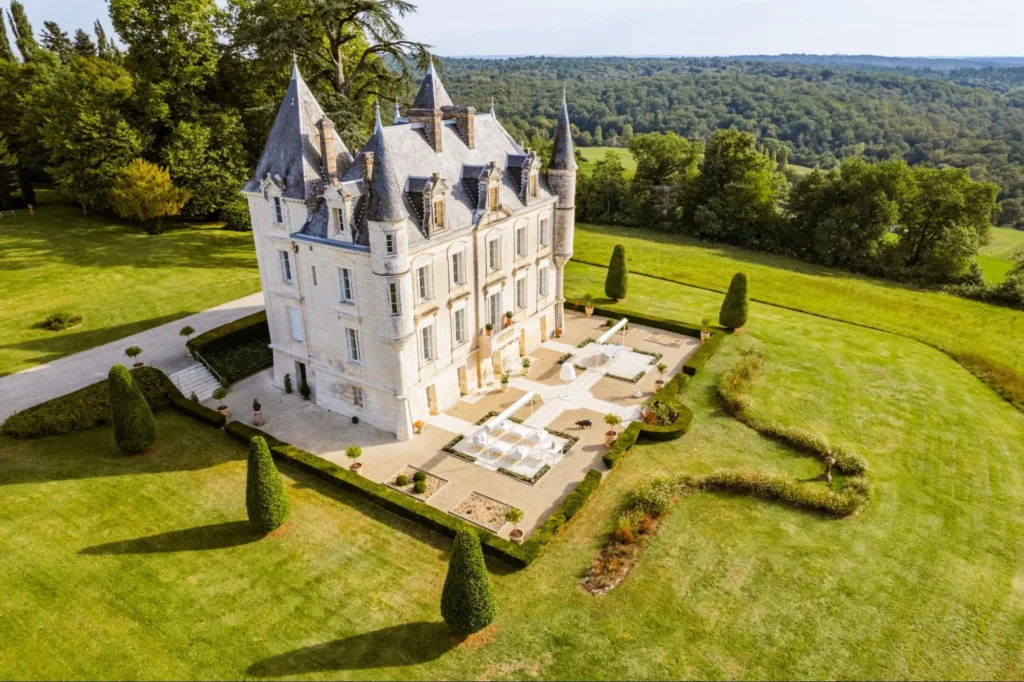 Grand French château surrounded by landscaped gardens and rolling countryside, offering a private luxury retreat.