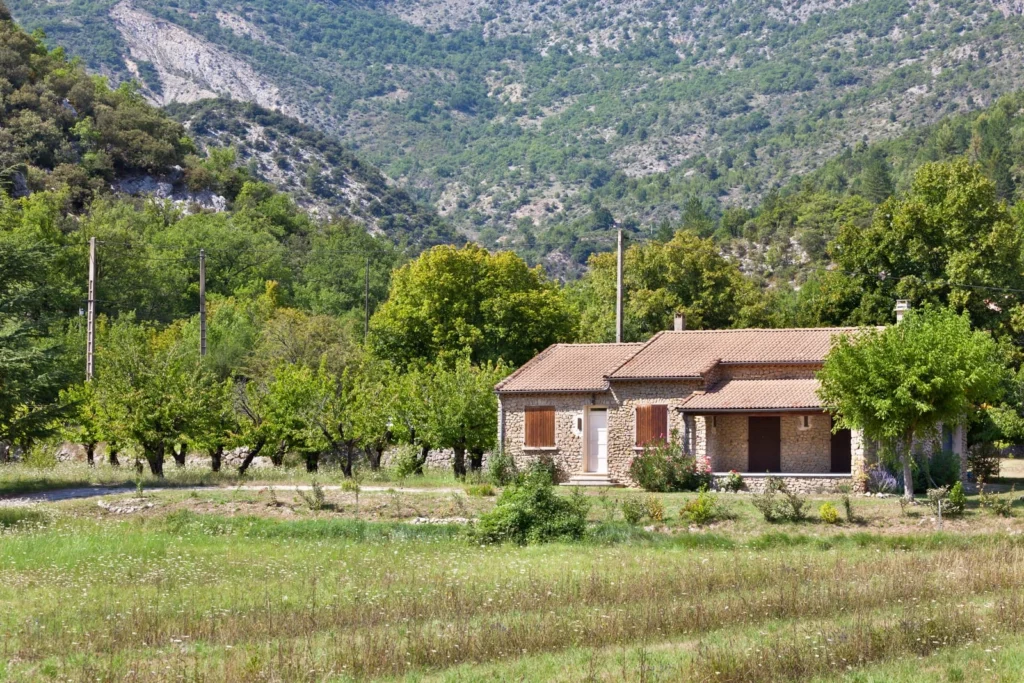 Stone cottage near mountains and green fields