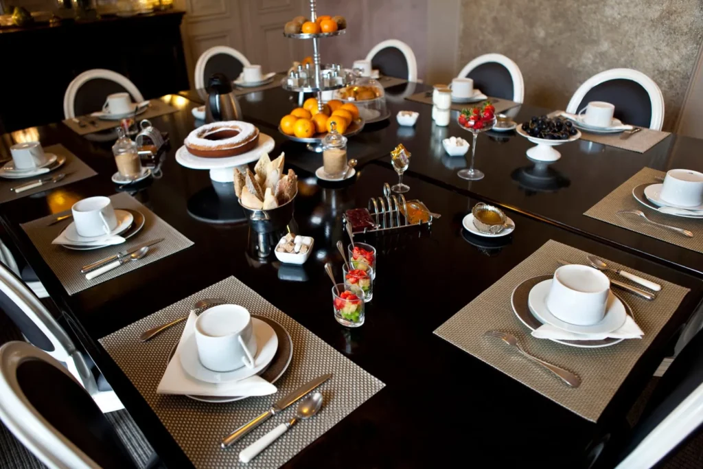 Stylish dining table with fresh fruit, pastries, coffee, and tableware arranged in a luxury South of France villa.