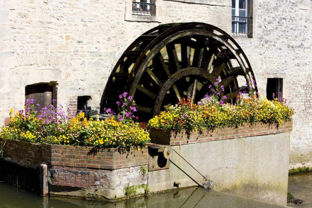 Old French water mill with flowers by the river