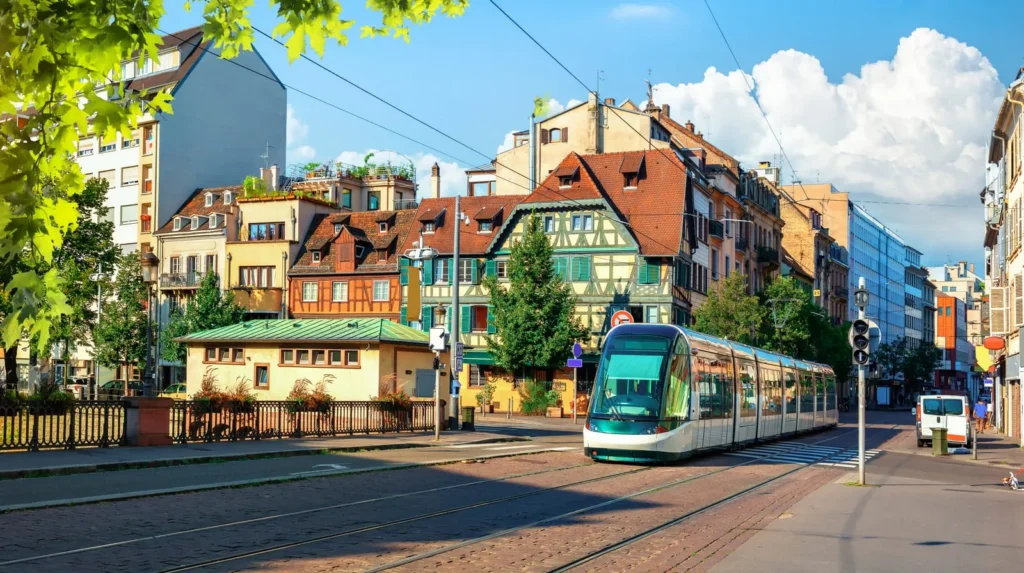 Modern tram passing through a colorful European city street.