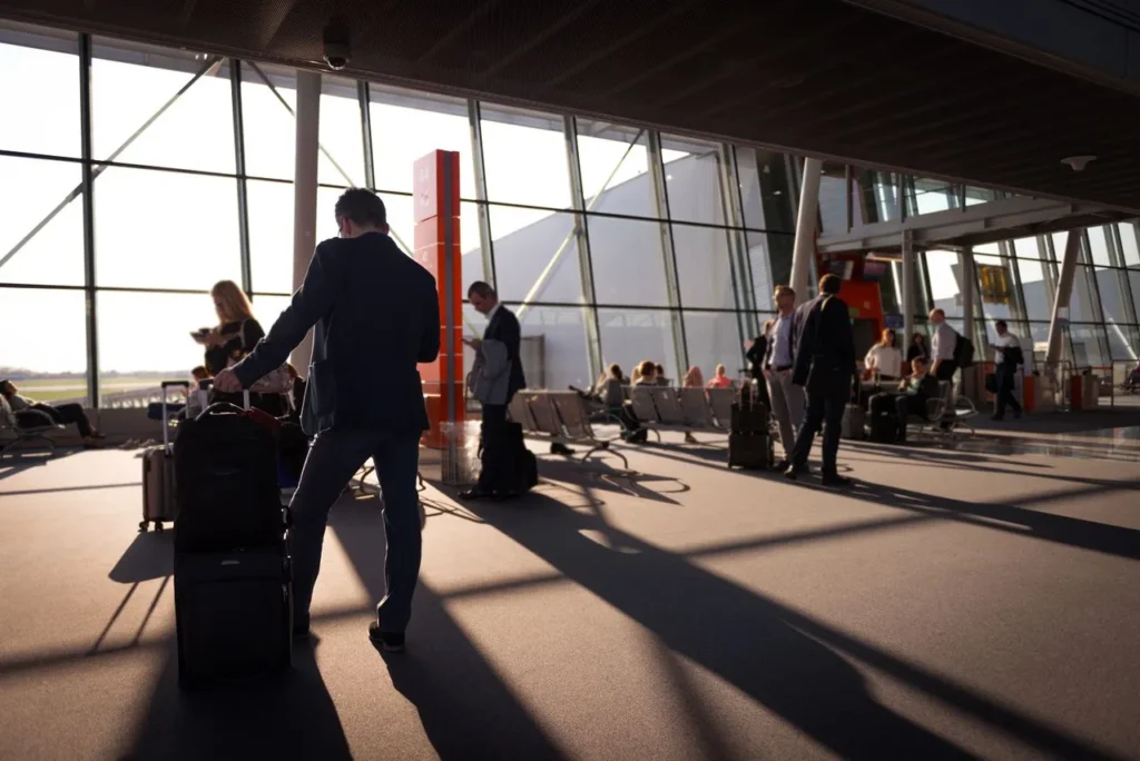 Travelers waiting with luggage inside an airport terminal