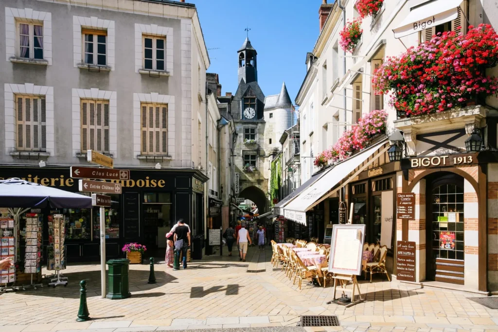 Charming French town street with cafes, flower boxes, shops, and historic clock tower