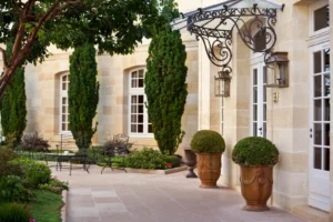 Refined chateau courtyard with stone façade, iron canopy, potted topiary, and garden seating