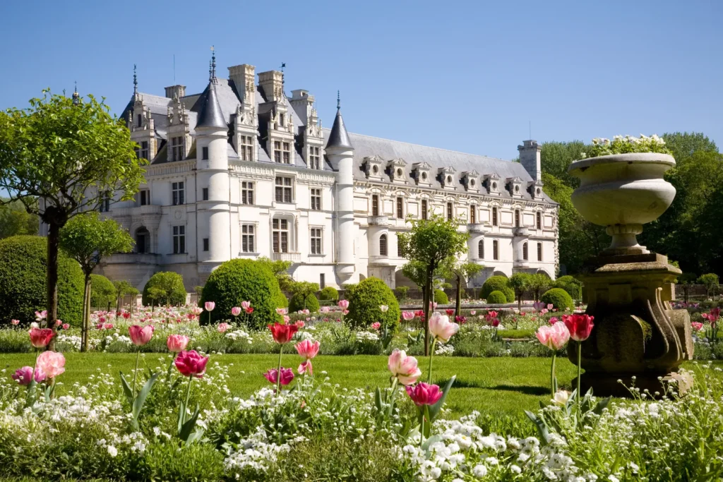 Elegant Loire Valley chateau behind spring flower gardens, trimmed trees, and stone fountain