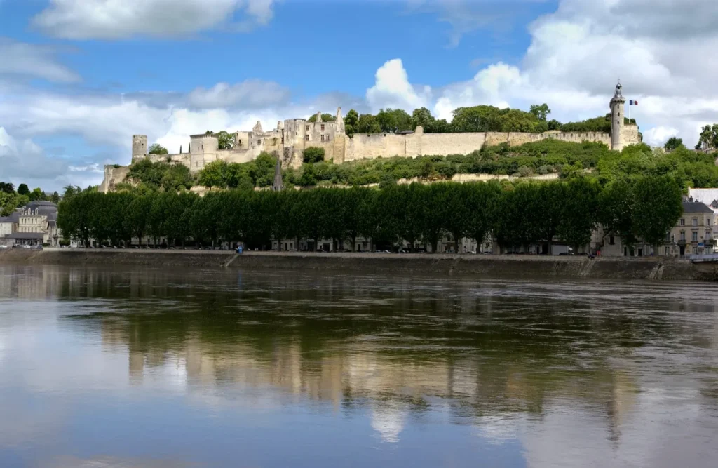 Medieval fortress overlooking the river with tree-lined banks and reflections on the water