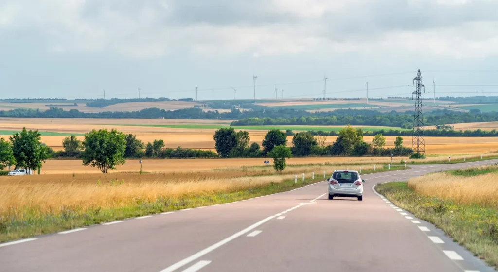 Car driving through open French countryside fields