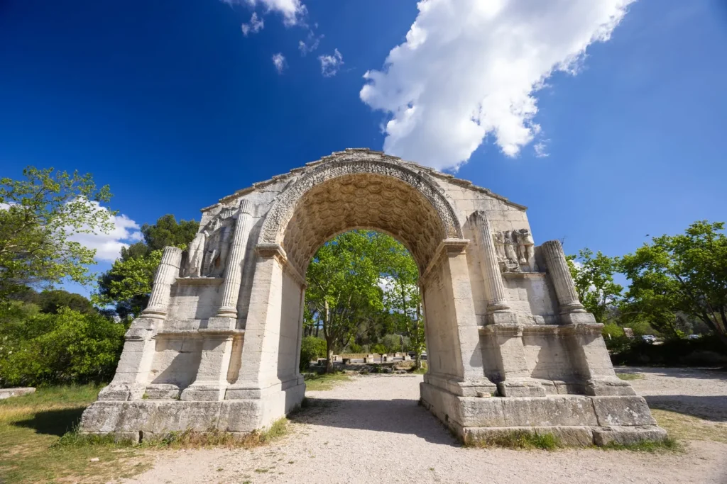 Ancient Roman stone arch at Glanum in Provence beneath a bright blue sky