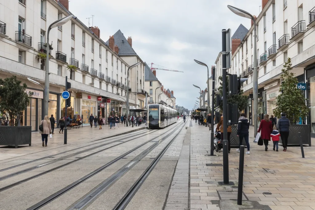 Modern tram passing through a busy pedestrian shopping street in Tours, France.