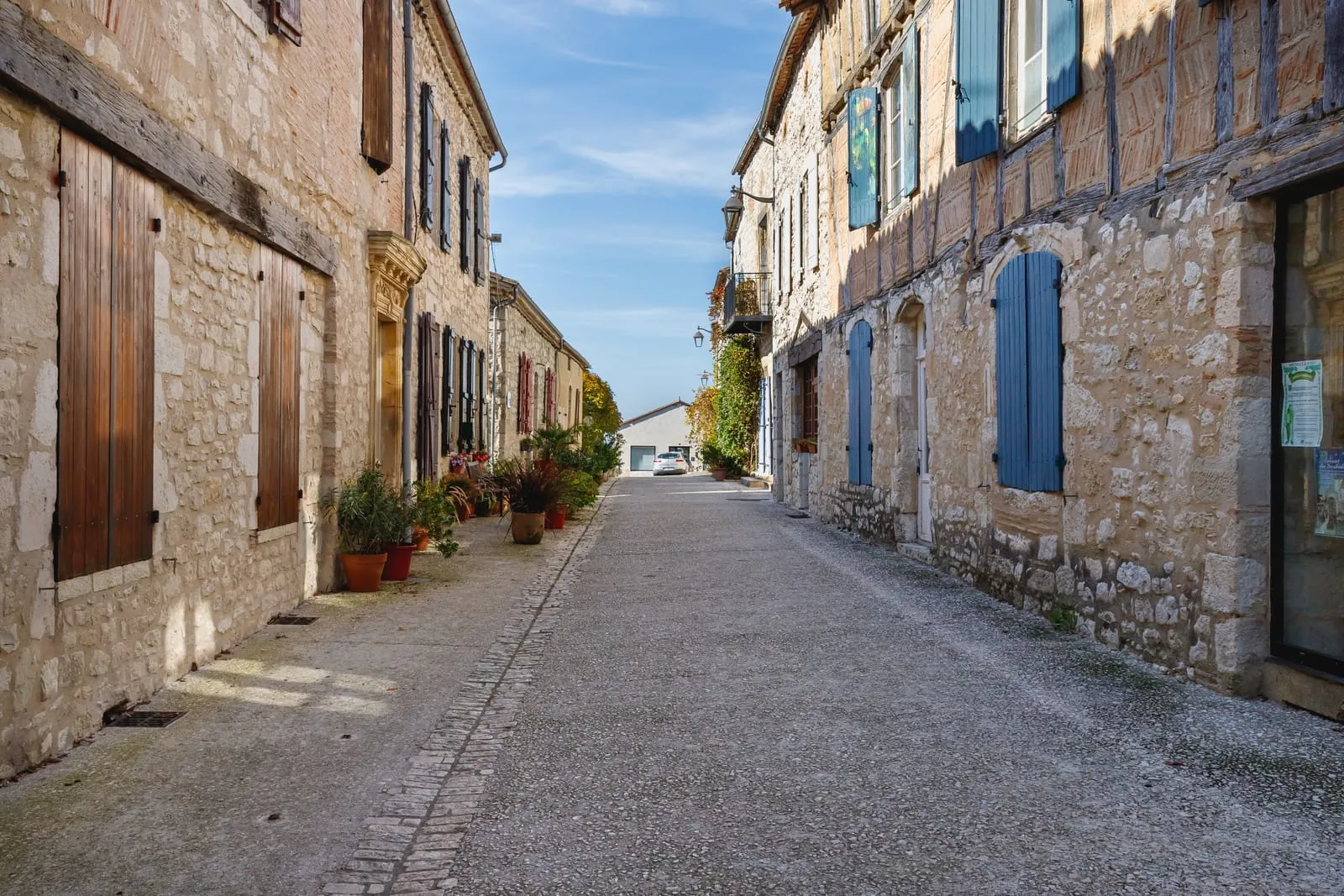 Quiet stone street with blue shutters in Eymet