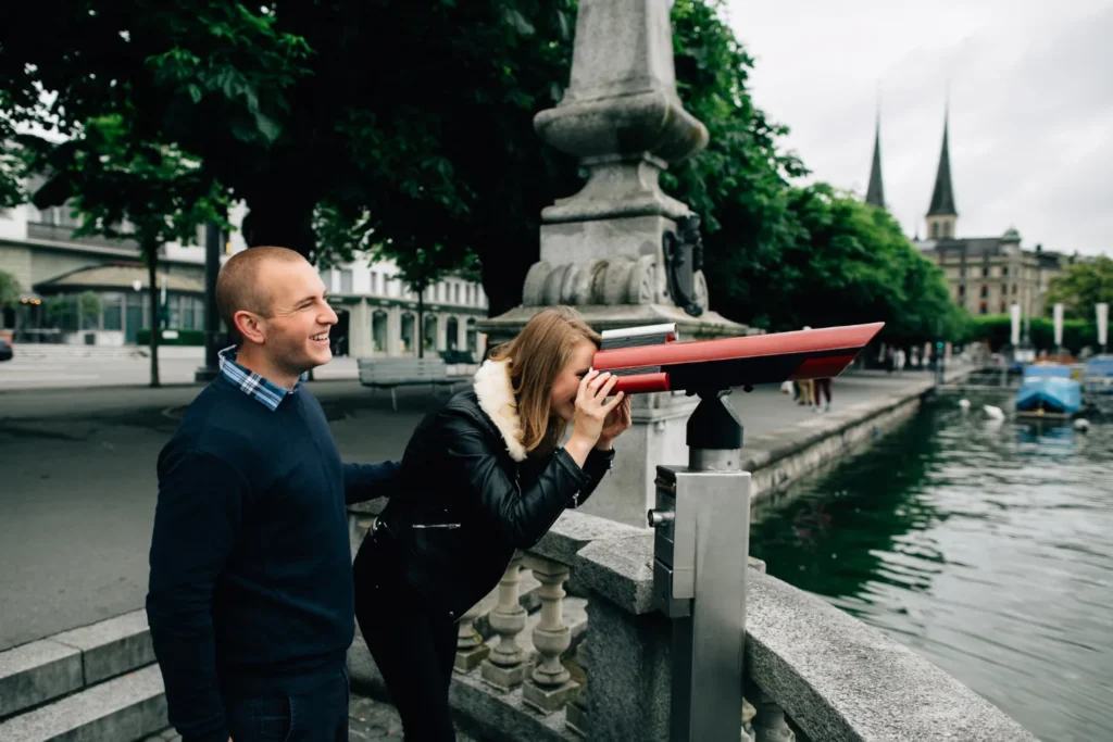 Couple using a viewpoint telescope by the river