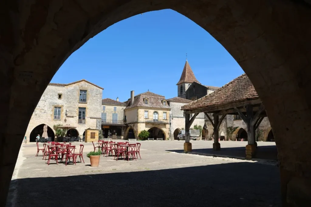 Monpazier square viewed through a stone arch