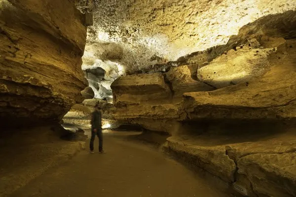 Visitor exploring a large limestone cave passage